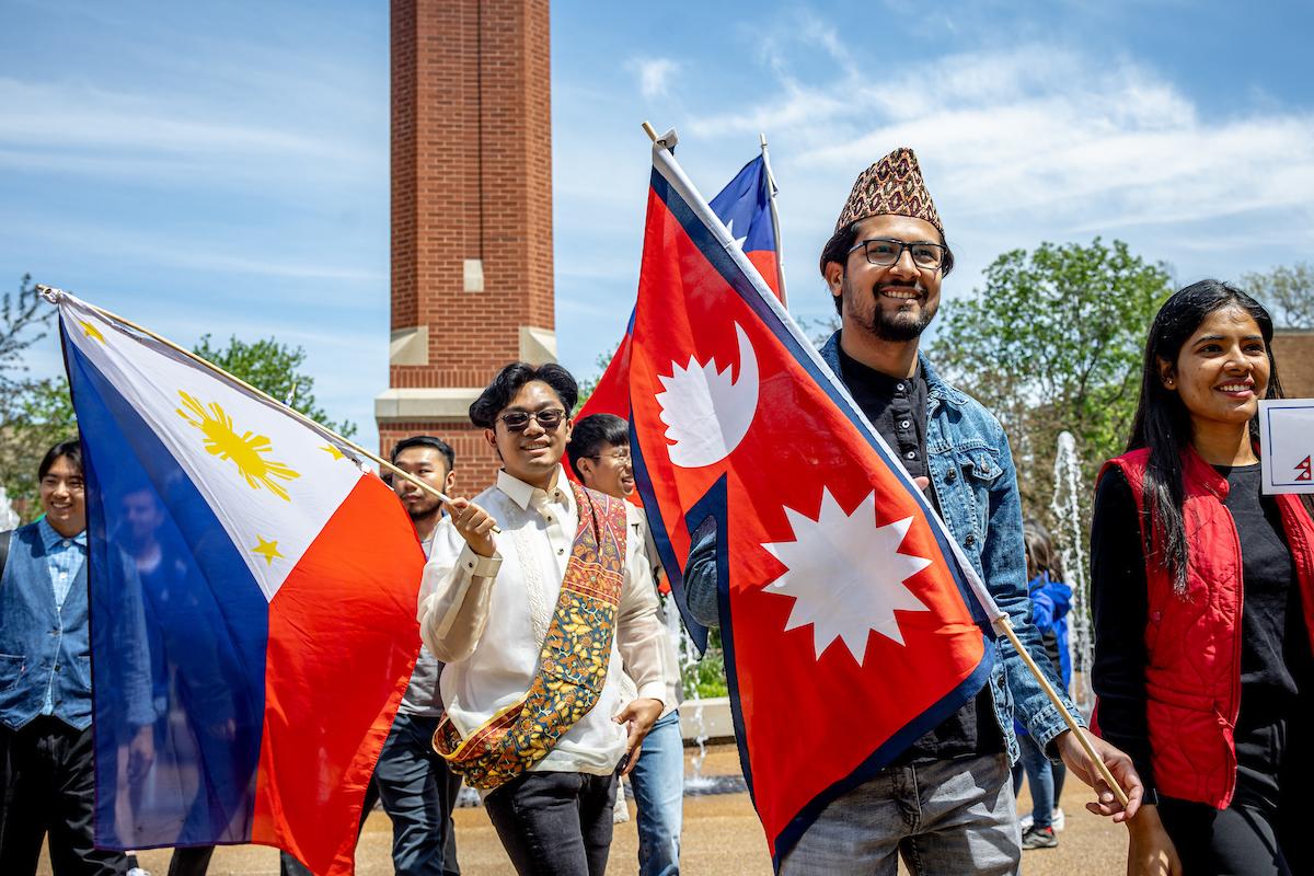 Slide 3: Students carry the flags representing Nepal and the Phillipines.