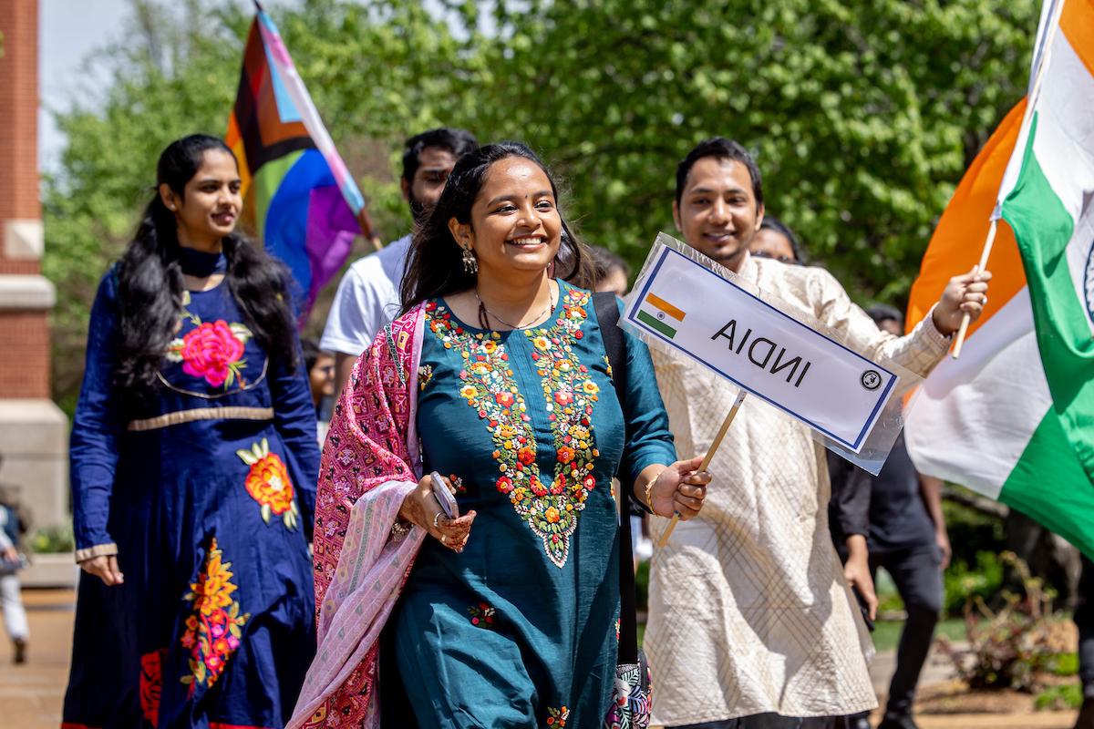 Slide 2: Students representing India walk in traditional dress.